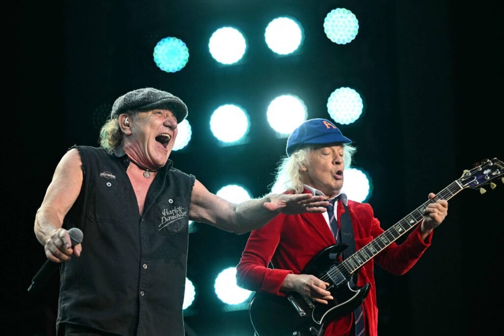 Brian Johnson (à esq.) e Angus Young (à dir.), da banda AC/DC, se apresentam no palco durante o show da "Power Up Tour" no Stade de France, em Saint-Denis, nos arredores de Paris, em 9 de agosto de 2025 - Julie Sebadelha/AFP